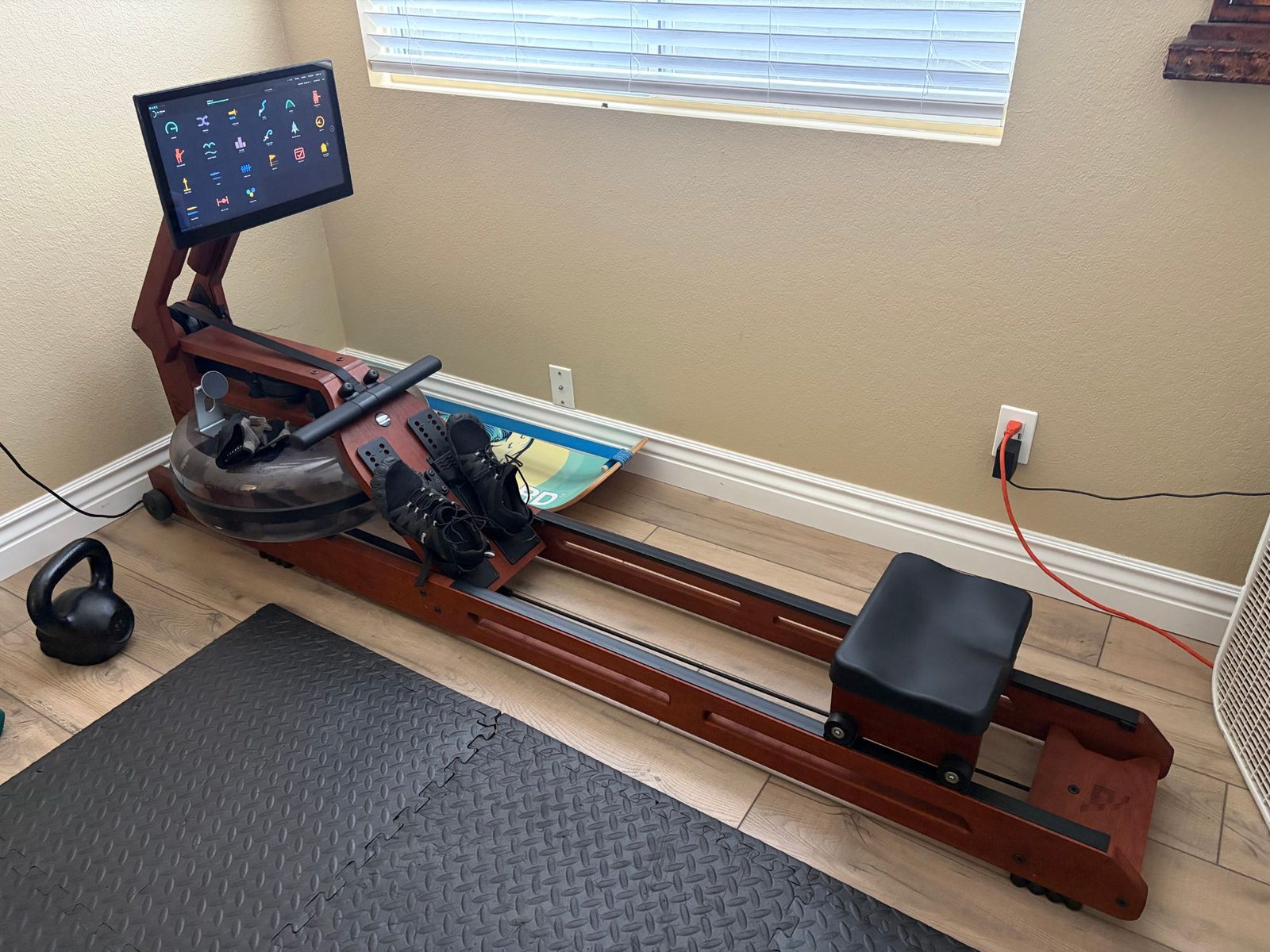 A WaterRower in an Ergatta fit-out, its tablet showing WAKE's home screen of game cards